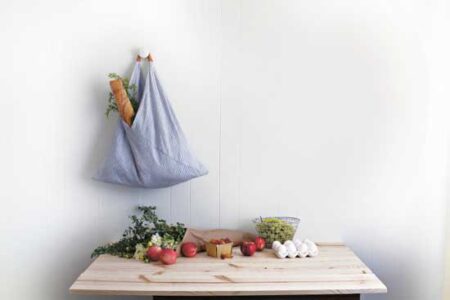blue triangular fabric bag hanging on a knob on the wall over a table with…